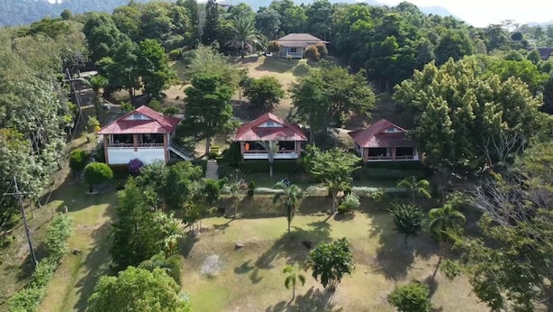 A cluster of three houses with red roofs, surrounded by dense greenery and trees. - Freedom Estate (Ko Lanta)