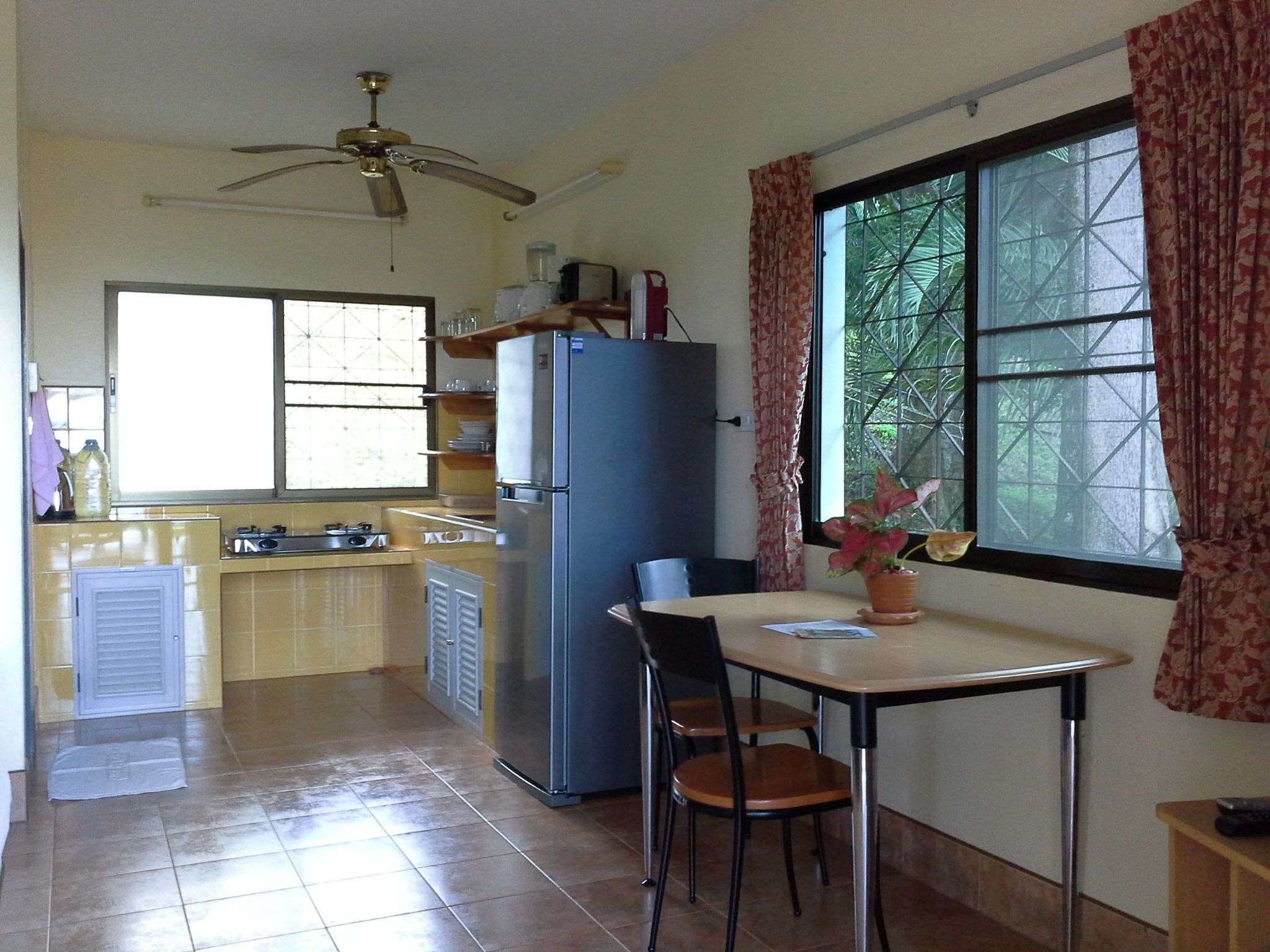 A compact kitchen with a refrigerator, stove, and dining table with chairs.