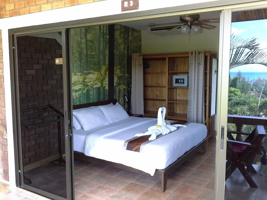 Un dormitorio con cama, armario de madera, una mesita y vistas al exterior.
