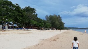 A sandy beach with a few people and trees in the background. - Freedom Estate (Ko Lanta)