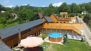 A wooden cabin with a pool, deck, and a covered patio area.