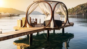 Une structure de lit flottant dotée d’une plateforme en bois et offrant une vue dégagée sur l’eau et les collines lointaines.
