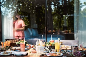 A buffet table with various foods and drinks, a pool in the background, and a person in pink attire. - Club Privé By Rixos Gocek - All Inclusive (Fethiye)