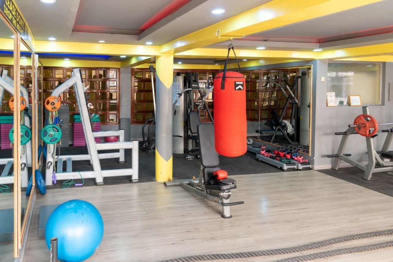 Un gimnasio con diversos equipos de ejercicio, que incluye un saco de boxeo, máquinas de pesas y una cinta de correr.