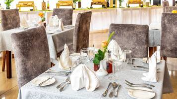A restaurant with tables set for dining, featuring grey upholstered chairs and white tablecloths.