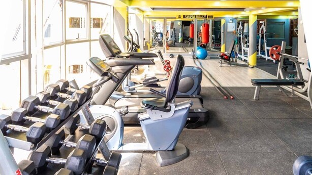 Een sportschool met loopbanden, gewichten en fitnessballen.