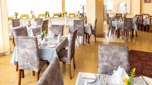 Een restaurant met gedekte tafels, met grijze gestoffeerde stoelen en lichtblauwe tafelkleden.