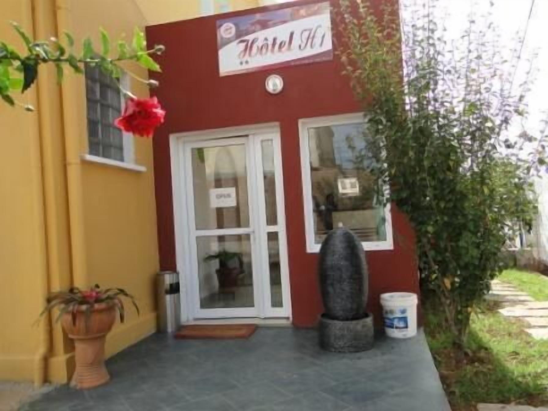 Entrada de un hotel con fachada roja, puerta de cristal y un letrero sobre la puerta.