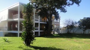 Un edificio de varios pisos con balcones, una escalera y un césped bien cuidado.