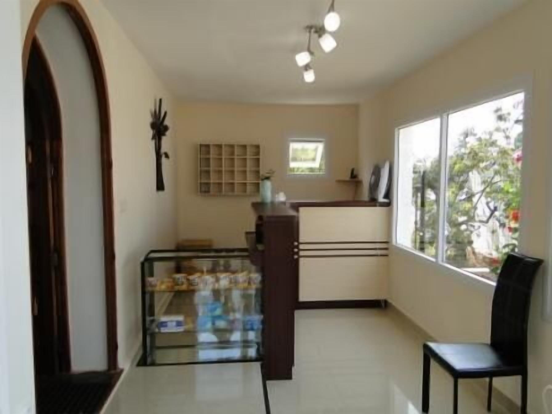A room with a glass display case, a wooden cabinet, a black chair, and a window with a view of trees.