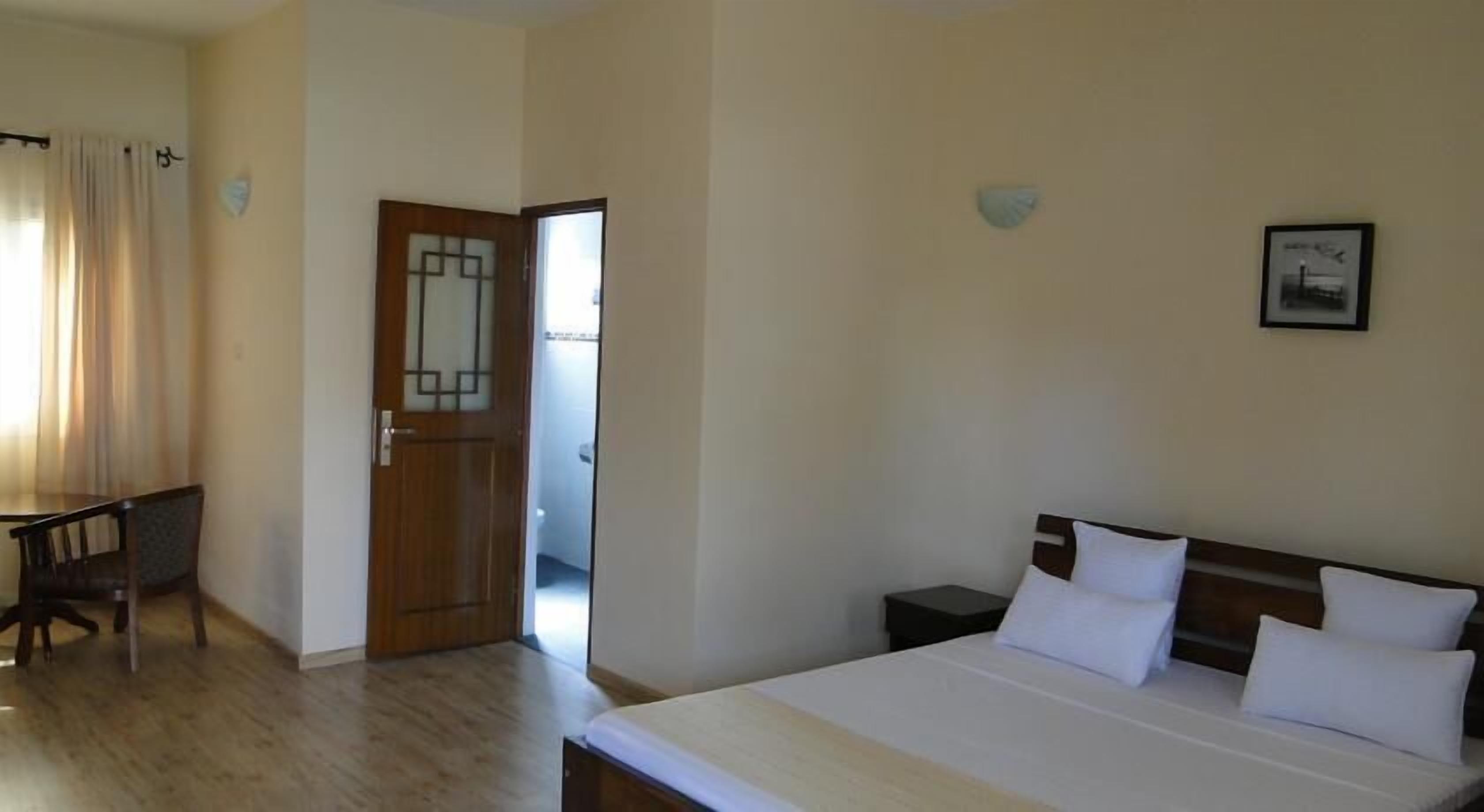 A hotel room with a bed, bedside tables, a desk, and a chair.