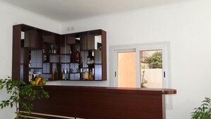 Una cocina moderna con una barra de madera integrada y estantes abiertos llenos de botellas.
