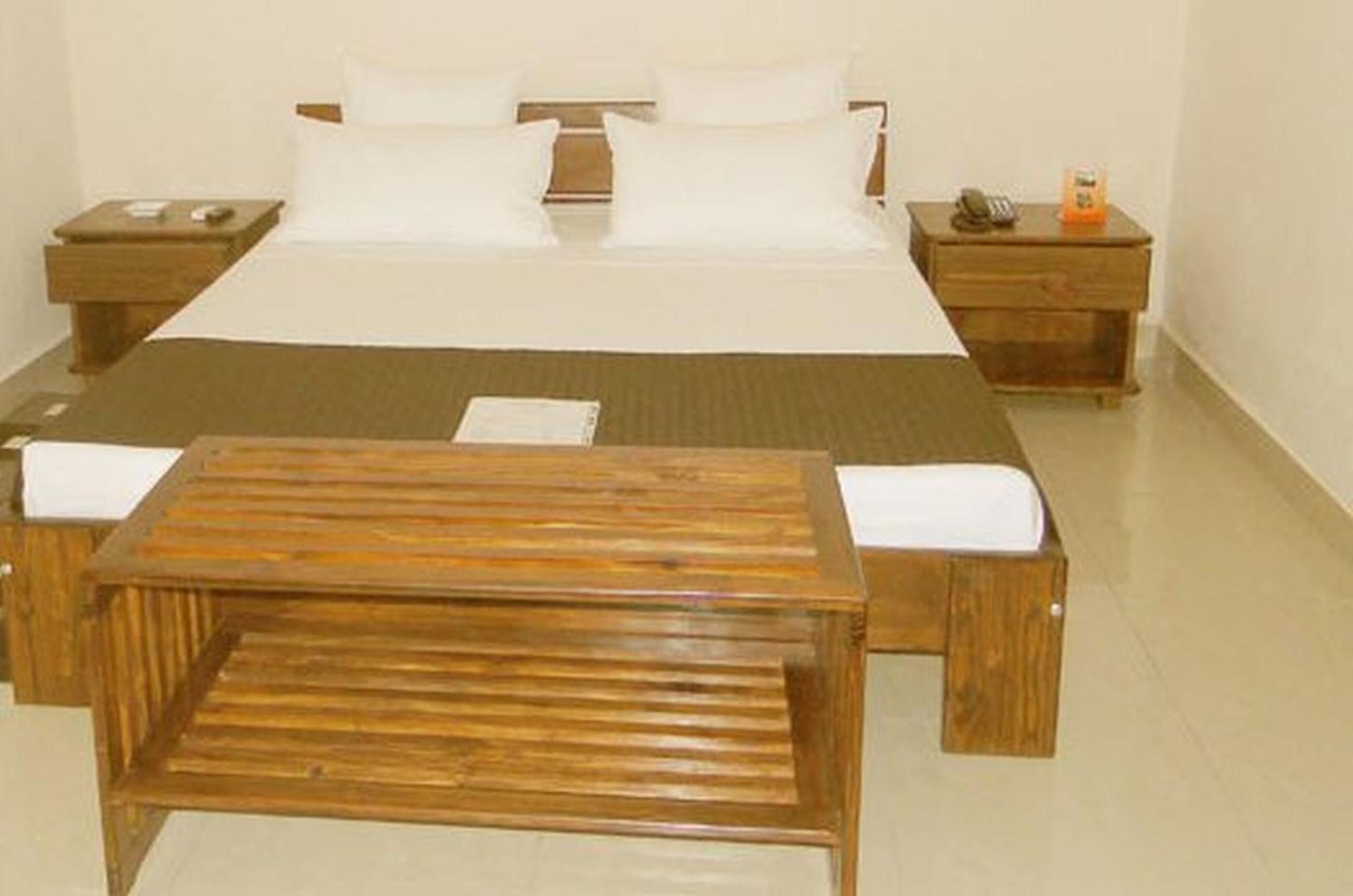 A neatly arranged hotel room with a large bed, two bedside tables, and a wooden bench.