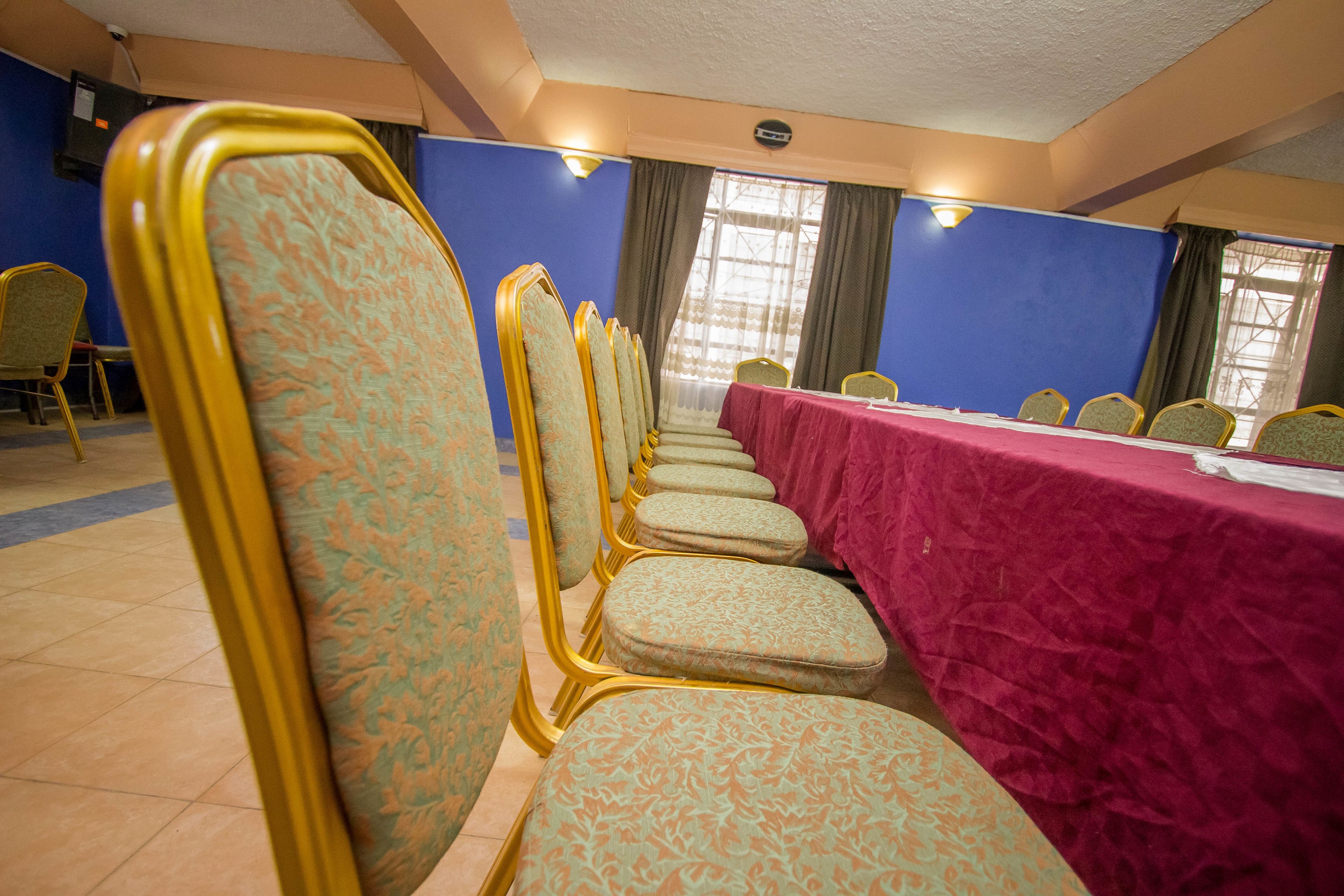A conference room with rows of chairs and a long table covered with a red tablecloth.