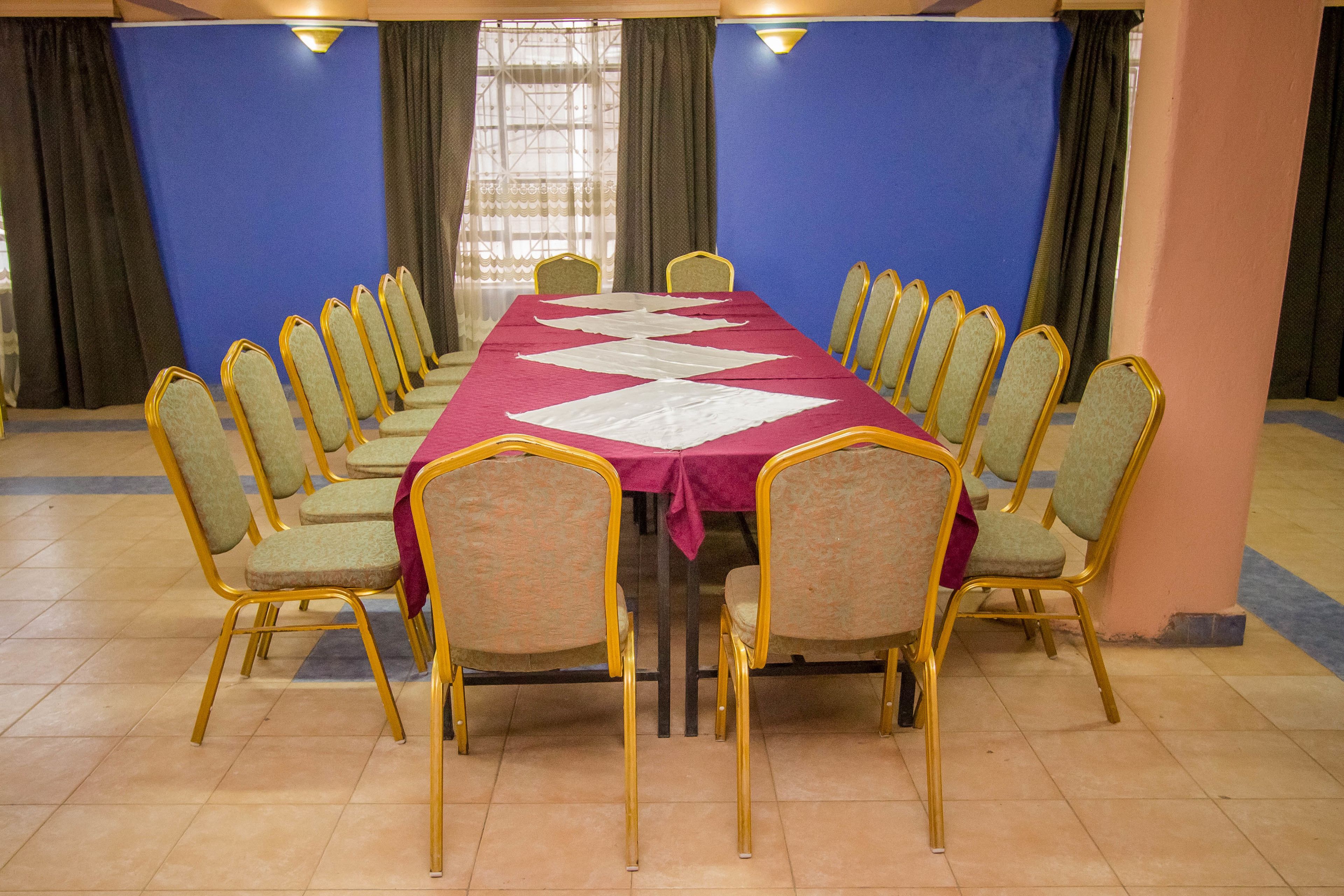 Un salón de conferencias con una larga mesa, varias sillas y cortinas.