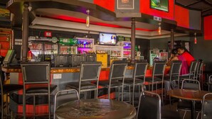 A bar area with multiple seating arrangements, a cash bar, and a television screen. - Hotel Nomad (Kitengela)