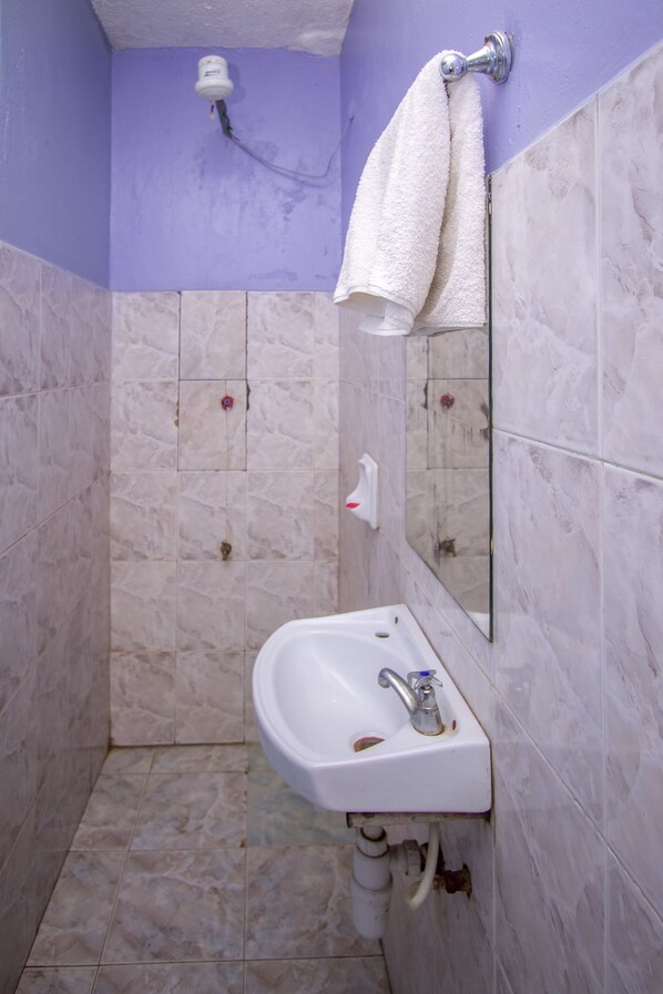 A bathroom with a white sink, a mirror, and a towel hanging on the wall.