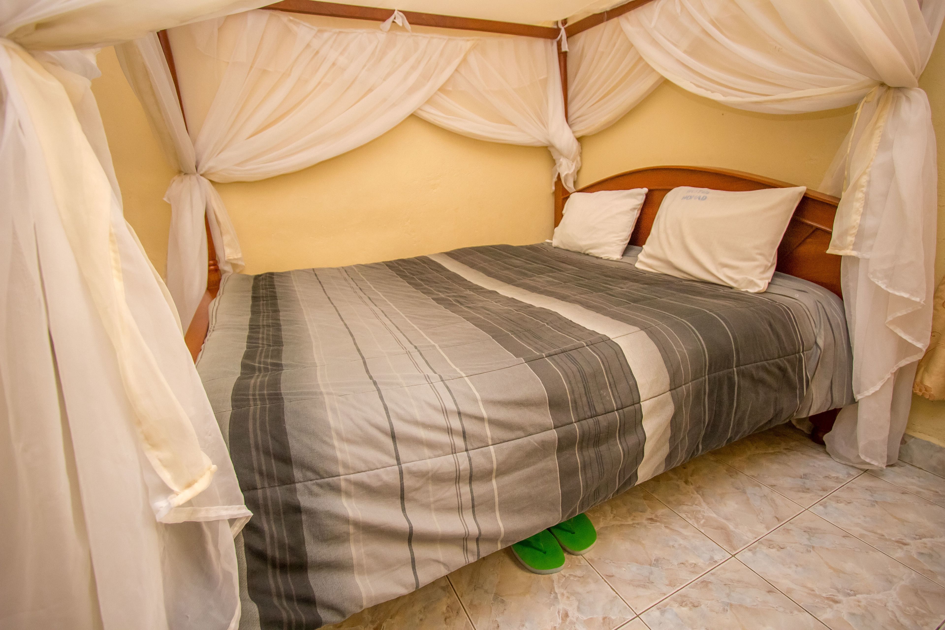 Een bed met een gestreept dekbedovertrek, witte kussens en een houten hoofdbord.