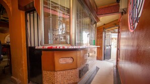 A hallway with a tiled floor, a wooden counter with a patterned tile base, and a metal gate. - Hotel Nomad (Kitengela)