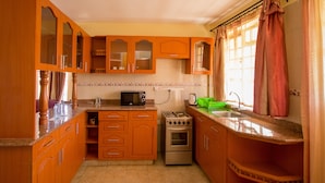 Une cuisine avec des meubles de rangement en bois, une cuisinière, un four à micro-ondes et un évier.
