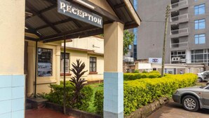 A reception area with a sign, a car parked outside, and a building in the background. - Impala Hotel (Nairobi)