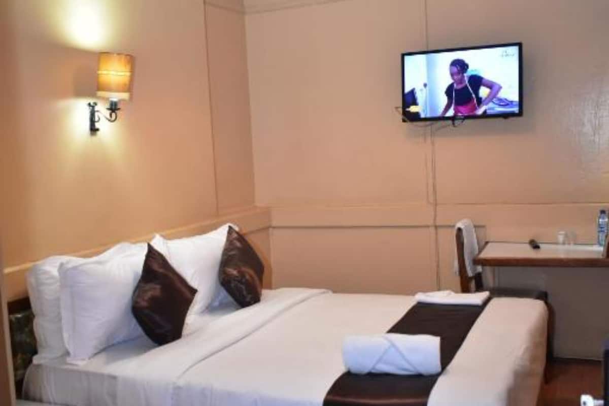 Habitación de hotel con cama, televisión montada en la pared, escritorio y silla.