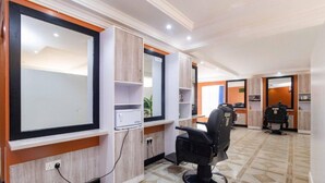 A modern hair salon with a large mirror, a black salon chair, and a tiled floor. - Impala Hotel (Nairobi)