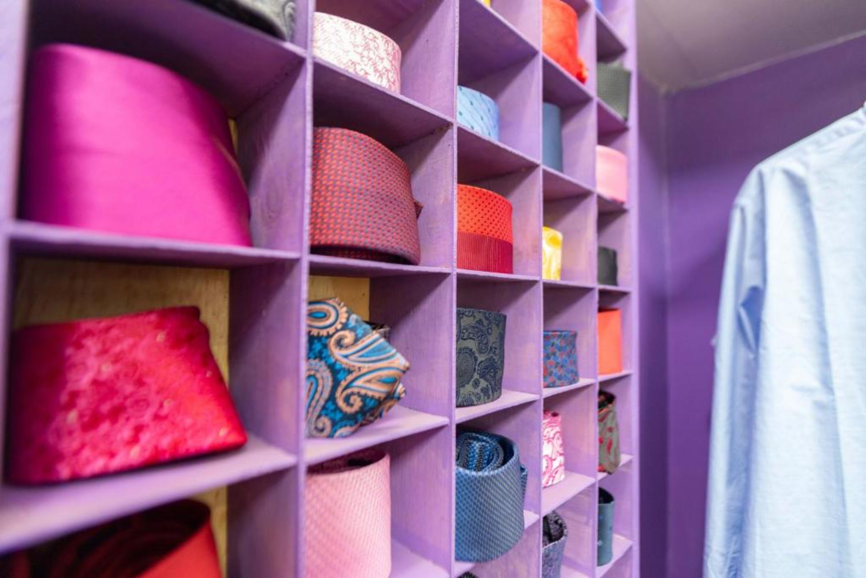 A storage unit with various rolled-up items, including pillows and fabric rolls, organized on shelves.