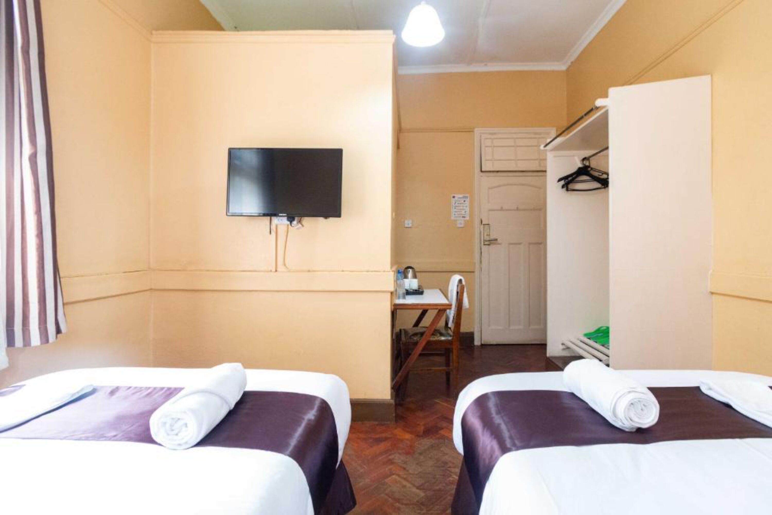 A hotel room with two beds, a TV, a desk, and a wardrobe.