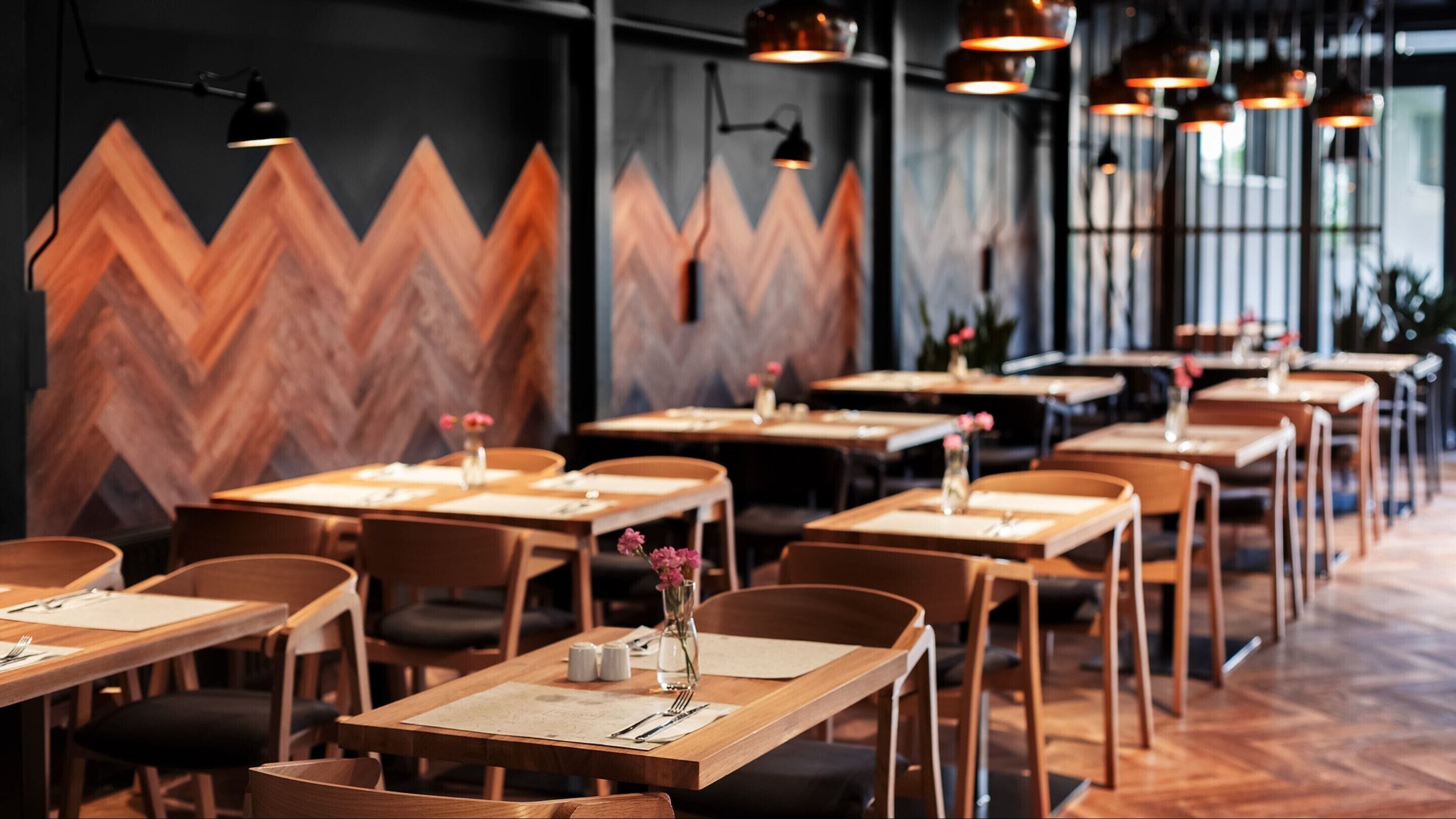 A restaurant with wooden tables and chairs, arranged in rows.