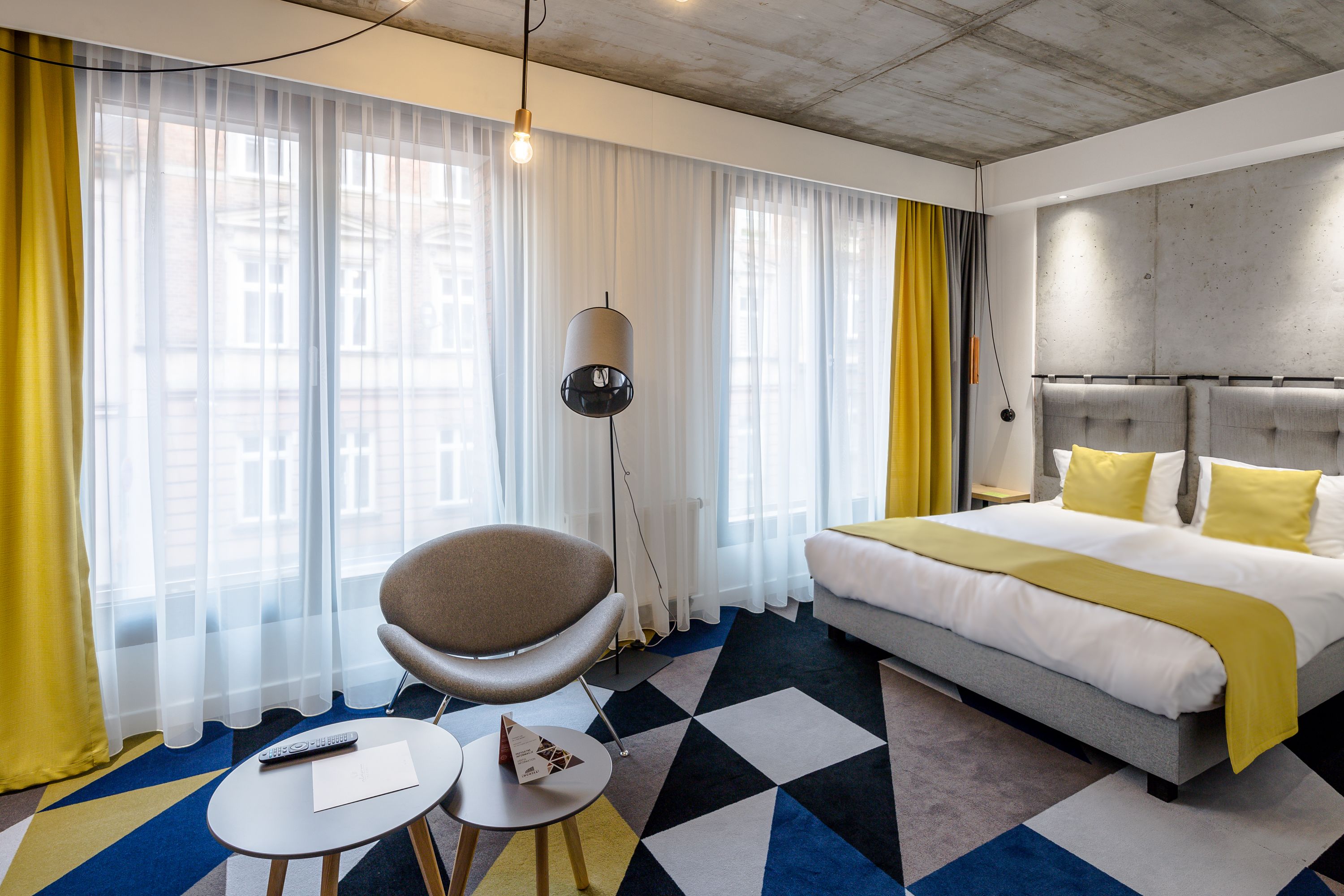 Une chambre d’hôtel avec un grand lit, une chaise, une petite table et une lampe.
