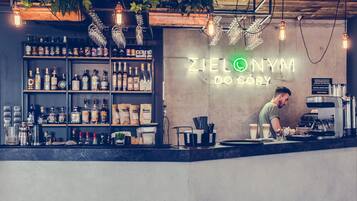 Un bar avec des étagères remplies de bouteilles d’alcool, un néon et une personne qui prépare des boissons.