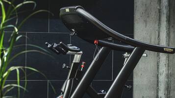 A stationary bike in a room with a tiled wall and a concrete pillar.