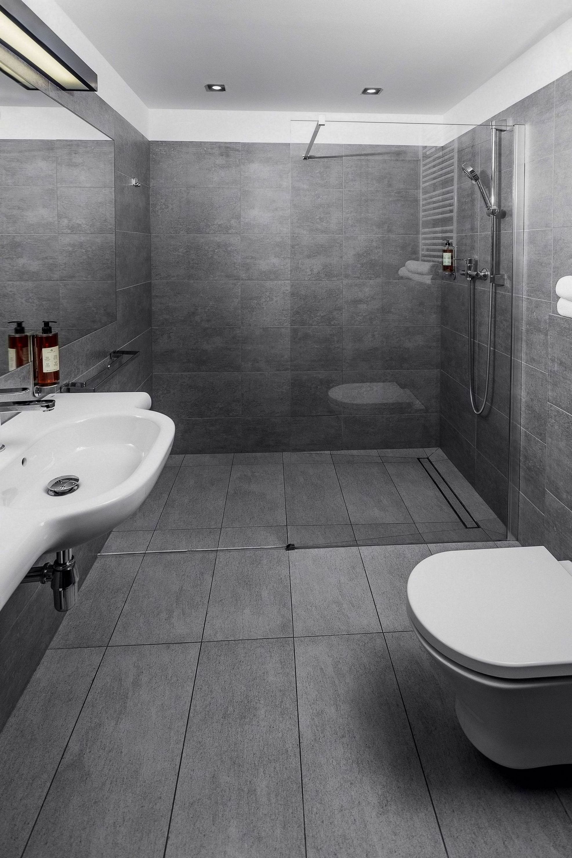 Un baño moderno con ducha, dos lavamanos y un inodoro.
