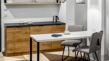 A modern kitchen with a white countertop, wooden cabinets, and a dining area with a white table and grey chairs.