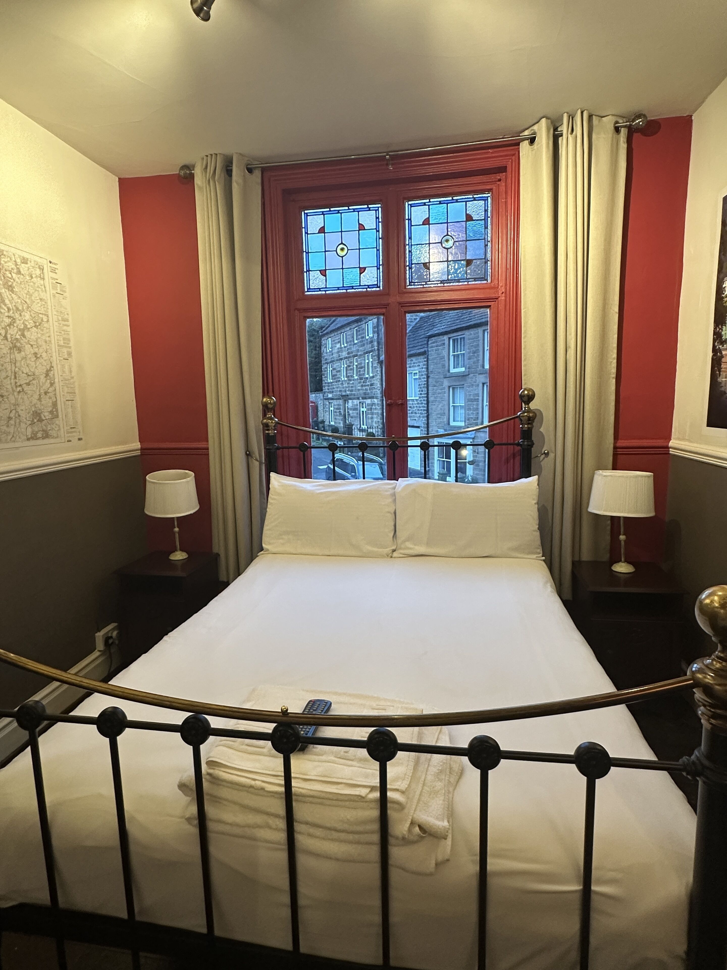 Habitación de hotel con cama, ventana con cortinas, mapa en la pared y vista de edificios.