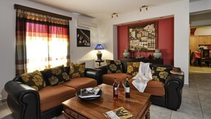 A living room with a sofa set, a coffee table with drinks, a lamp, and a painting on the wall. - Villa Jazz Rock (Corfu)
