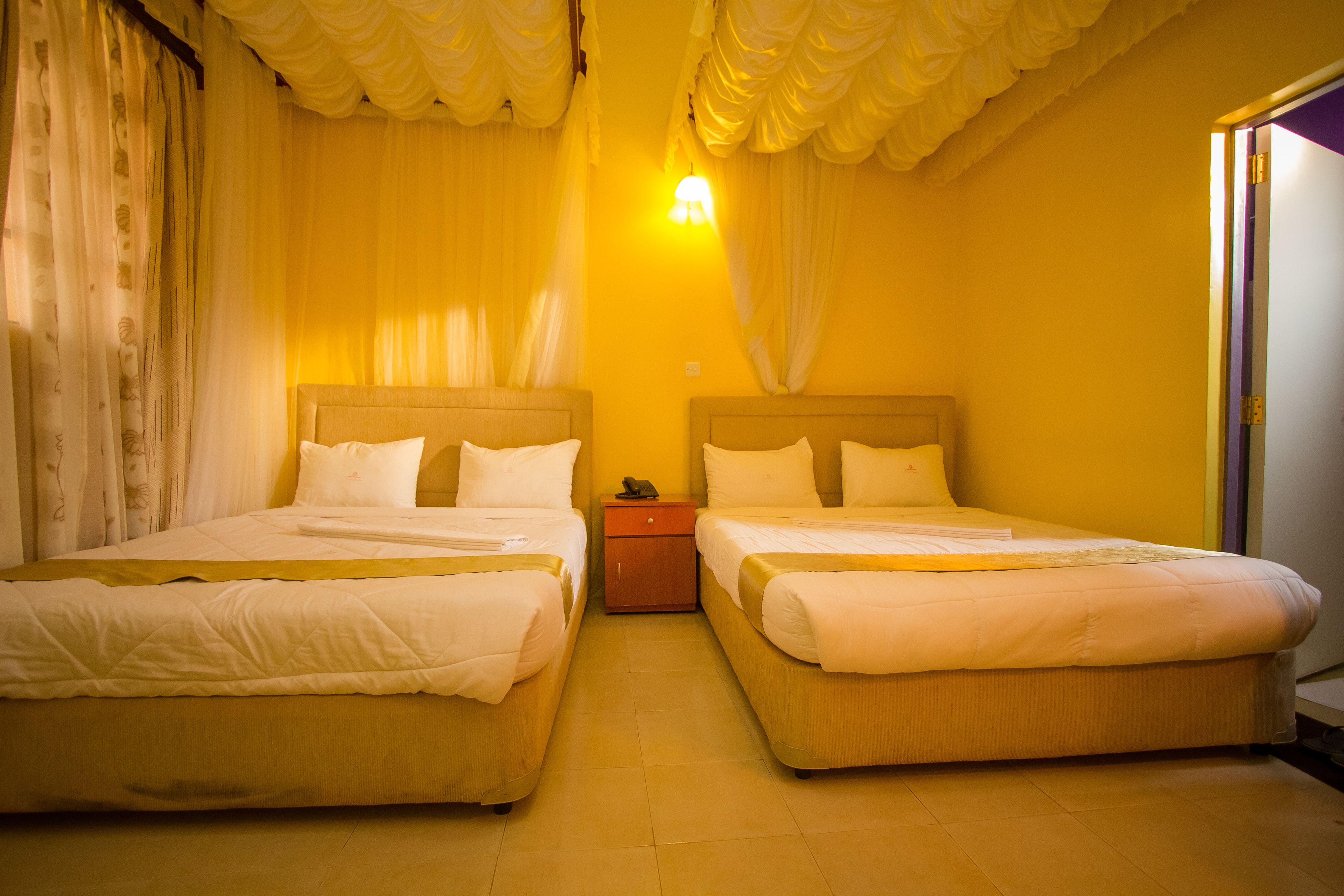 Habitación de hotel con dos camas, una mesita de noche y una lámpara.