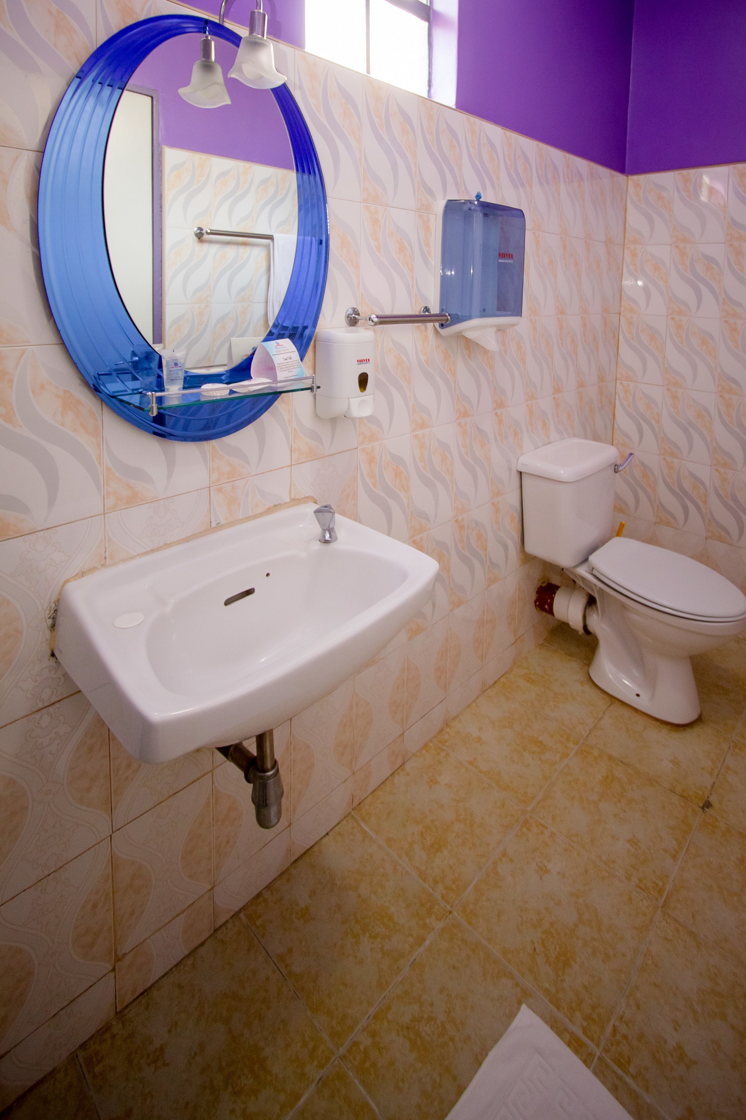 A bathroom with a white sink, a toilet, and a blue-framed mirror.