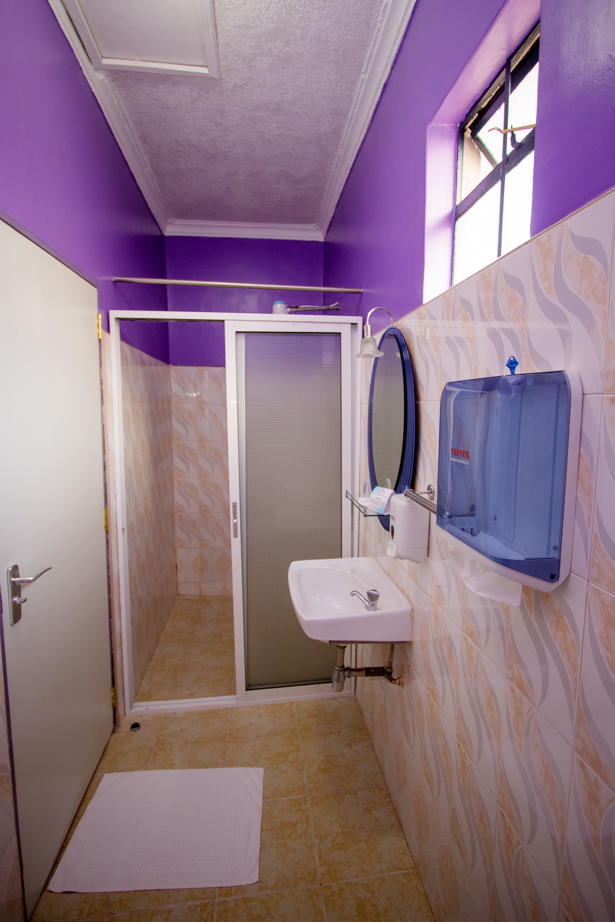 A bathroom with a shower, a sink, and a hand dryer.
