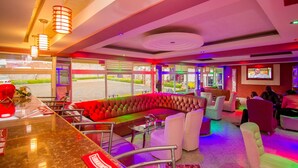 Een moderne loungehoek met een leren bank, witte fauteuils en een marmeren bar.