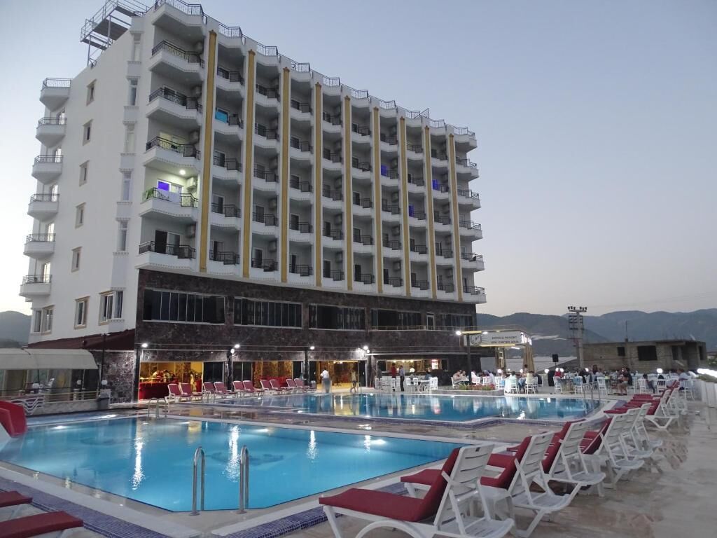 Een hotel met een zwembad, meerdere balkons en een bar/loungeruimte.