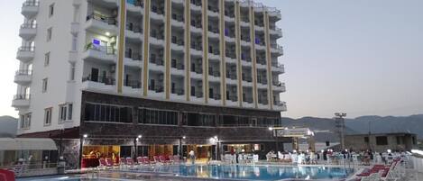 Un hotel con piscina, varios balcones y un bar-salón.