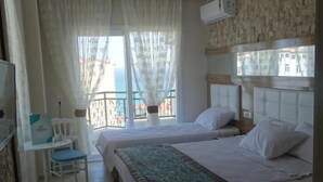 A hotel room with two beds, a small desk, and a chair.