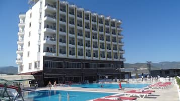 Un hôtel à plusieurs étages doté d’une piscine, d’un espace extérieur aménagé et offrant une vue sur les montagnes.