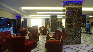 A lobby with red velvet armchairs, marble columns, and a reception area.