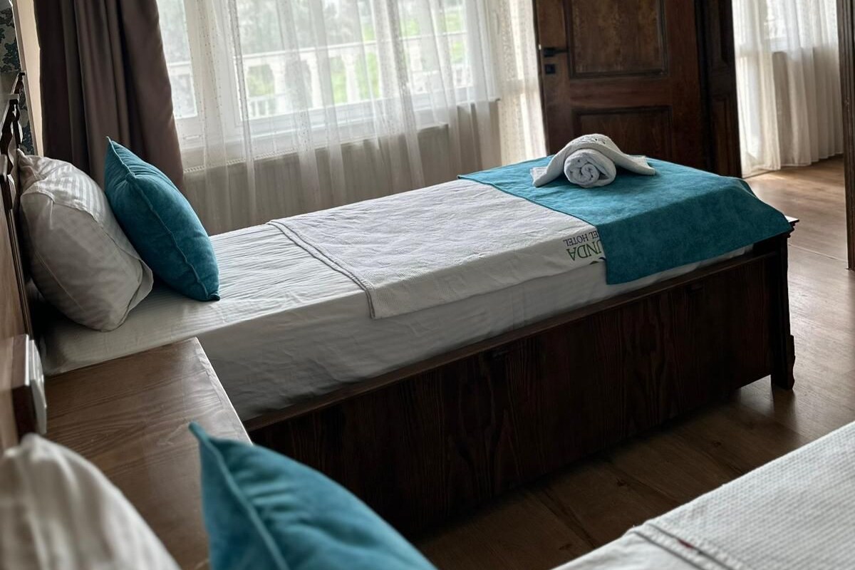 A bedroom with a bed, a wooden door, and a window with curtains.