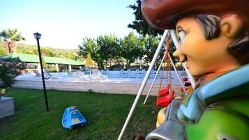 Relax by the pool surrounded by lush greenery and a playful statue.