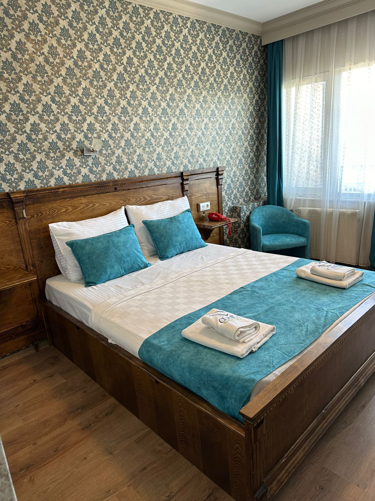 A neatly made bed with a wooden headboard, a blue throw blanket, and matching pillows.