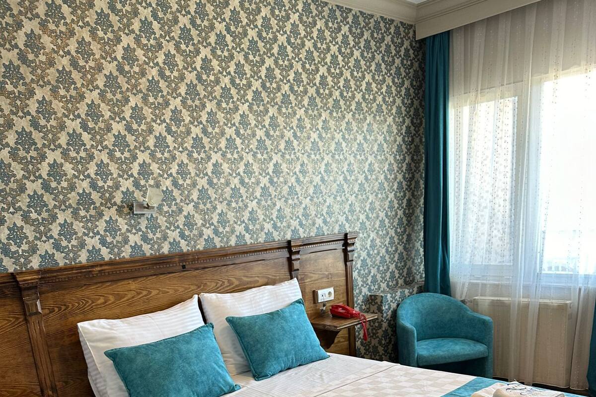 A neatly made bed with a wooden headboard, a blue throw blanket, and matching pillows.